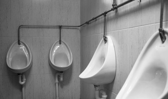 Plumbing - grayscale photography of four white ceramic urinal sinks