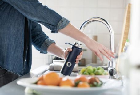 Faucet - person in blue denim jacket holding stainless steel bottle