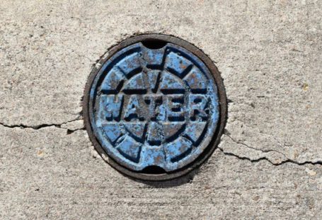 Drain - a manhole cover on a sidewalk with the word repair painted on it