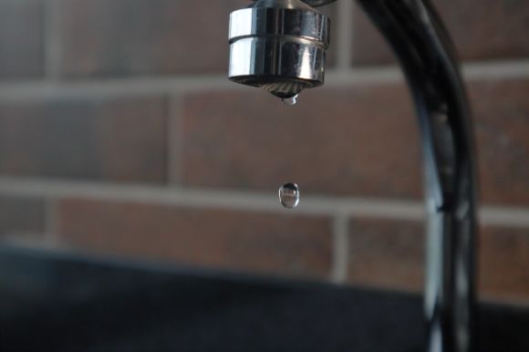 Faucet - a faucet with a water drop hanging from it