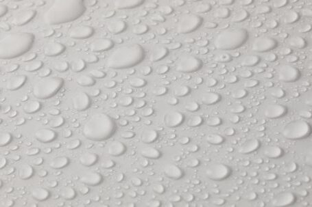 Water Heater Leaks - Closeup top view of plain wet abstract surface with small dripped water drops of different shapes placed on white background